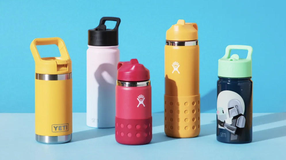 An array of five kids' water bottles of varying sizes and colors on a teal background. There are two bright yellow, one raspberry red, one pink, and one Star War-themed.